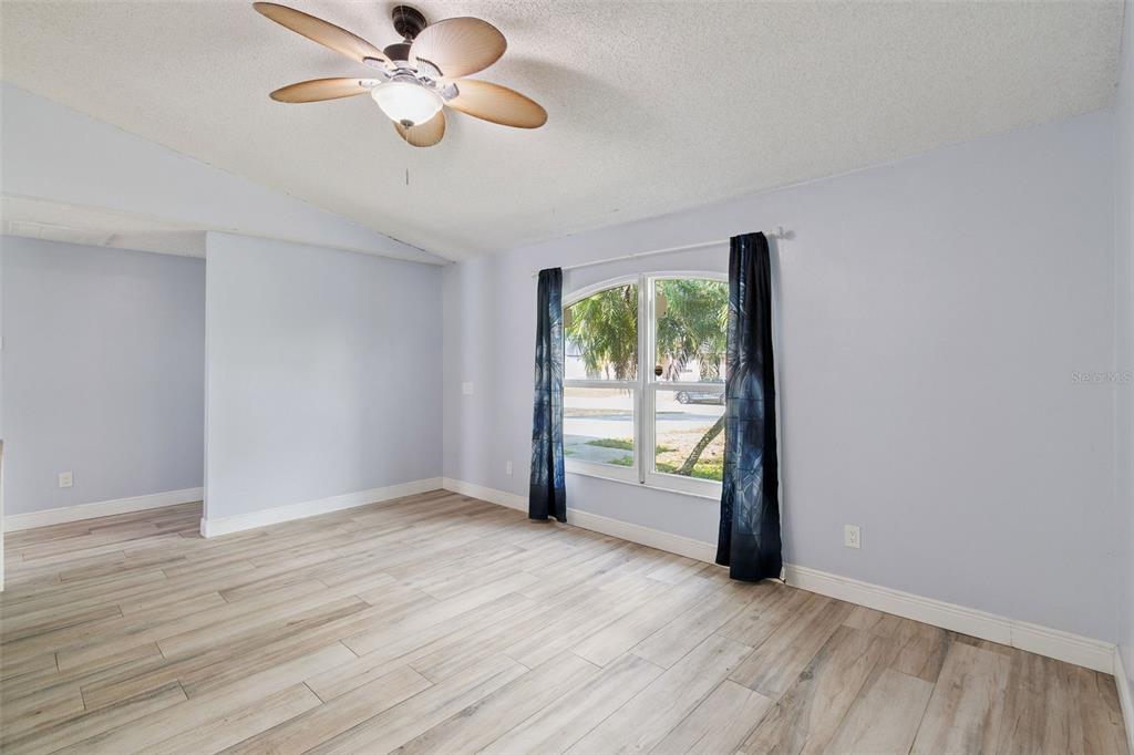An empty room with light blue walls, wood-look tile flooring, and a ceiling fan — 3349 SW FRANKFORD STREET, PORT ST LUCIE, FL