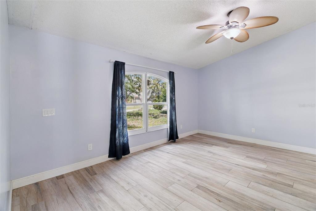 An empty bedroom with light blue walls, wood-look tile flooring, and a ceiling fan — 3349 SW FRANKFORD STREET, PORT ST LUCIE, FL