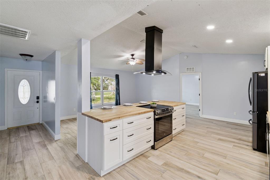 A kitchen features a white island with a butcher block countertop and a range hood — 3349 SW FRANKFORD STREET, PORT ST LUCIE, FL