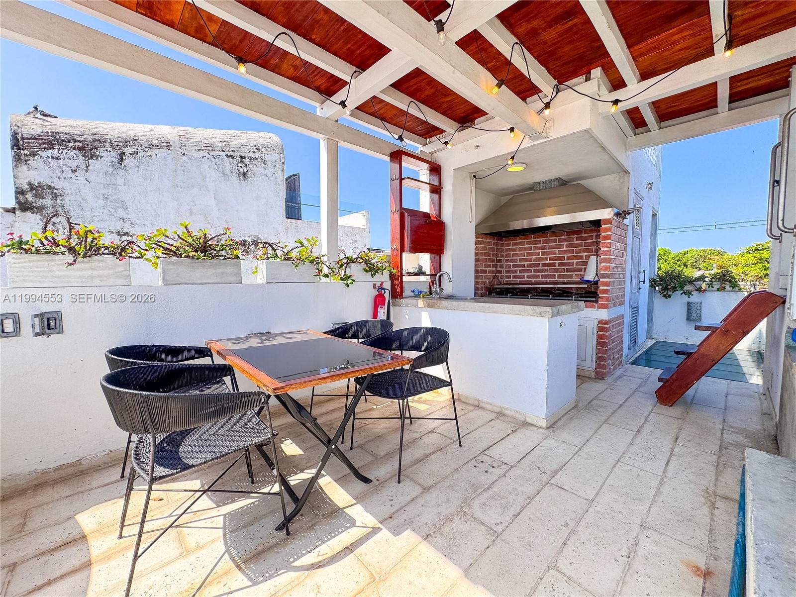 An outdoor rooftop terrace features a dining set, a brick grill, and a wooden pergola — El Pedregal Cartagena, Colombia, OU 0, OU