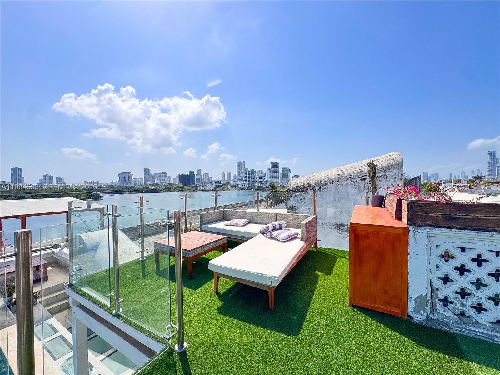 A rooftop terrace features artificial turf, outdoor furniture, glass railings, and a city skyline view — El Pedregal Cartagena, Colombia, OU 0, OU