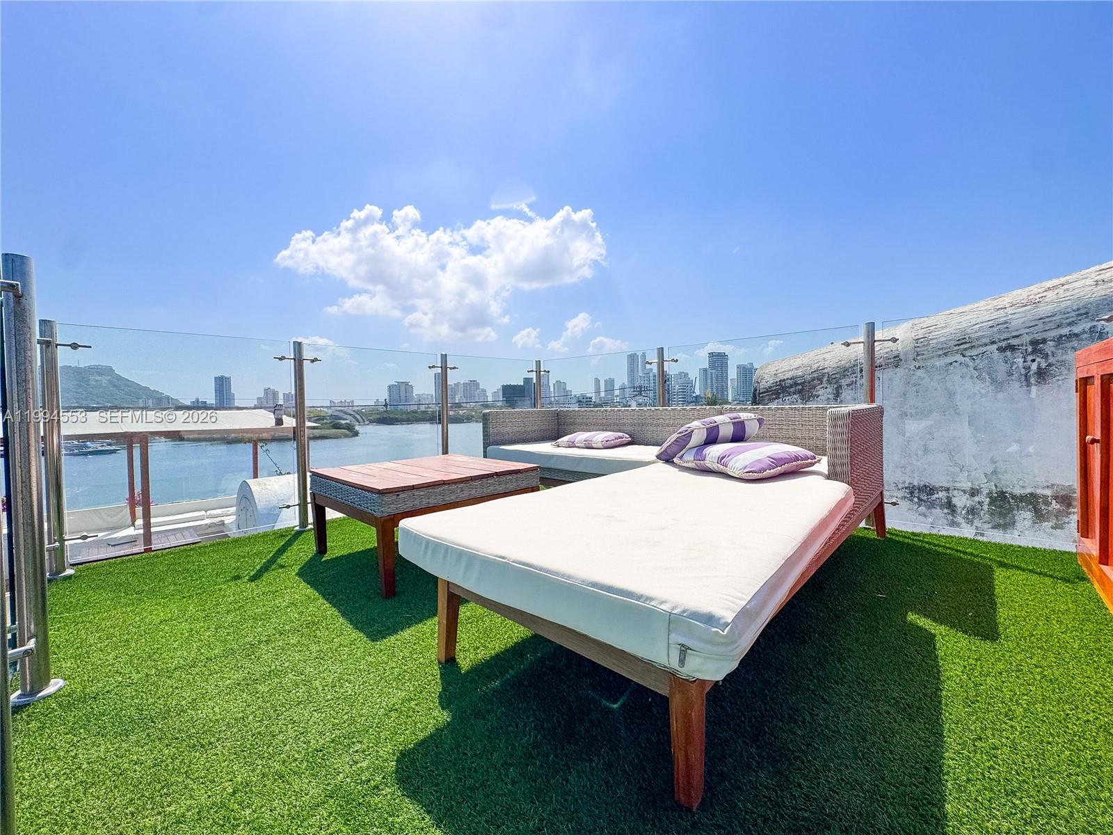 A rooftop terrace features artificial grass, outdoor lounge furniture, and a glass railing overlooking water — El Pedregal Cartagena, Colombia, OU 0, OU