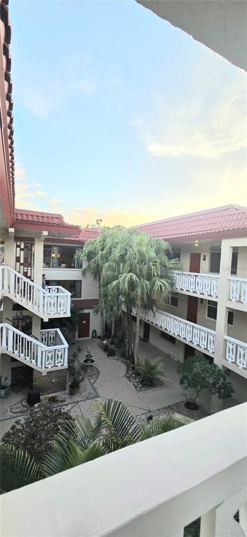 An elevated view of a multi-story apartment complex courtyard with palm trees and white railings — 1012 PEARCE DRIVE UNIT 307, CLEARWATER, FL