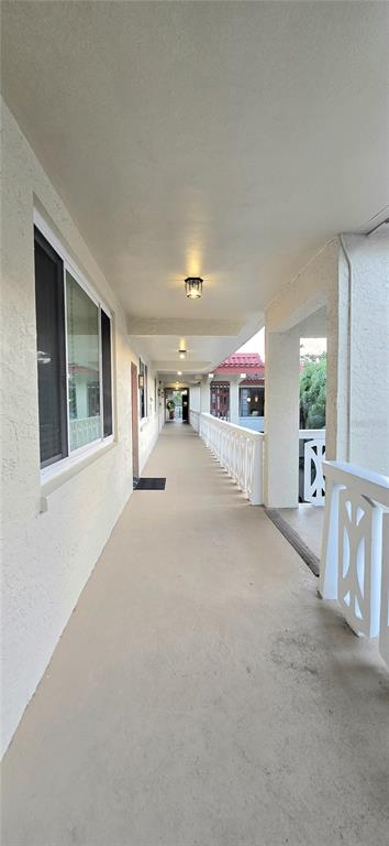 An outdoor covered walkway with a concrete floor, white railings, and wall-mounted light fixtures — 1012 PEARCE DRIVE UNIT 307, CLEARWATER, FL