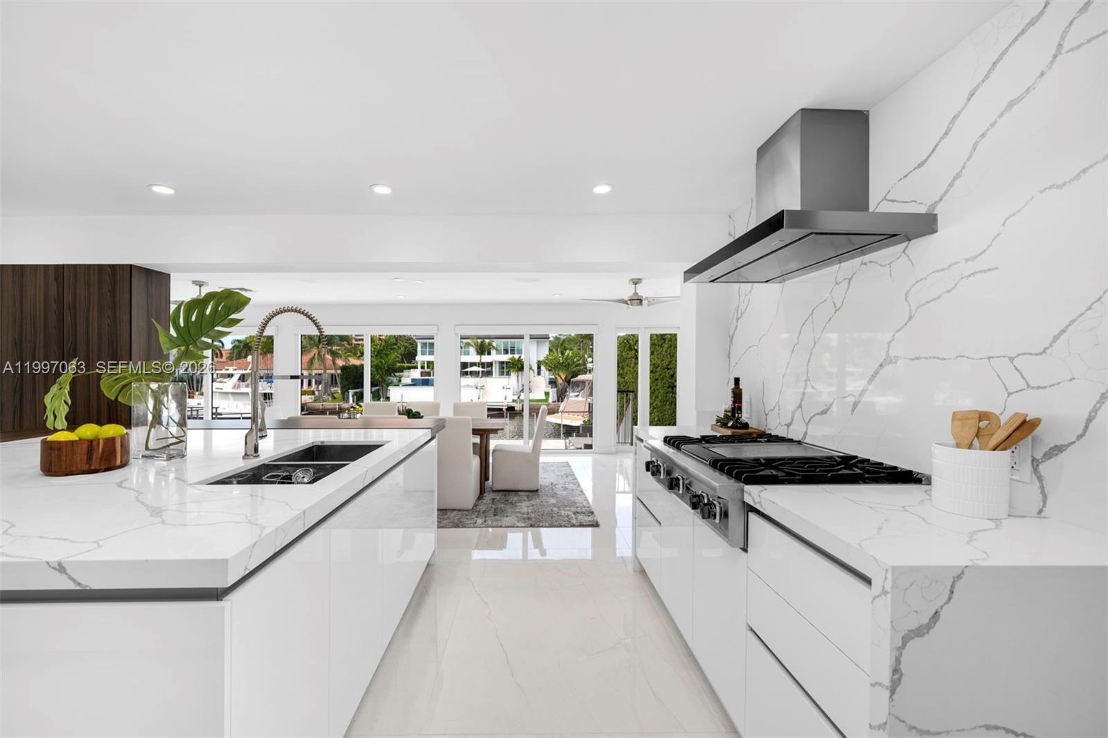 A modern white kitchen features marble countertops, a gas range, and a view of water — 6832 Sunrise Ct # 0, Coral Gables FL 33133, CORAL GABLES, FL