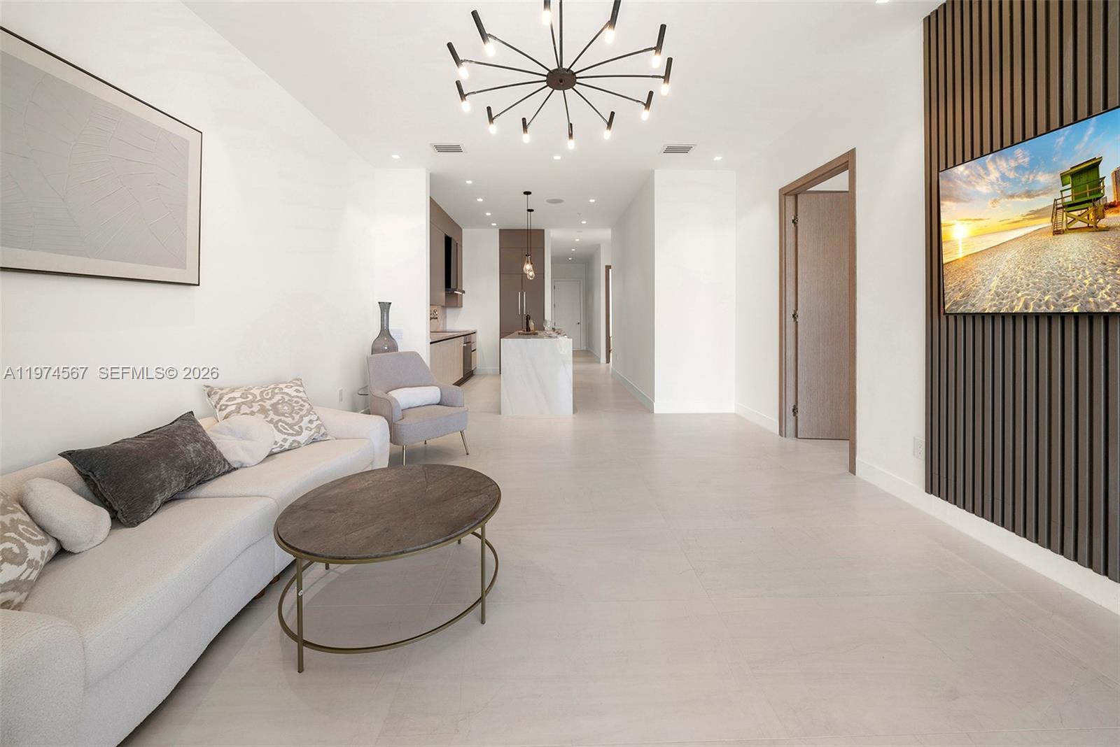 This modern living room features a white sofa, a coffee table, and a wall-mounted television — 246 NE 6th Ave # 302, Delray Beach FL 33483, DELRAY BEACH, FL