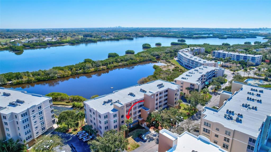 An aerial view shows several multi-story apartment buildings situated near a large body of water — 6475 SHORELINE DRIVE UNIT 5102, ST PETERSBURG, FL
