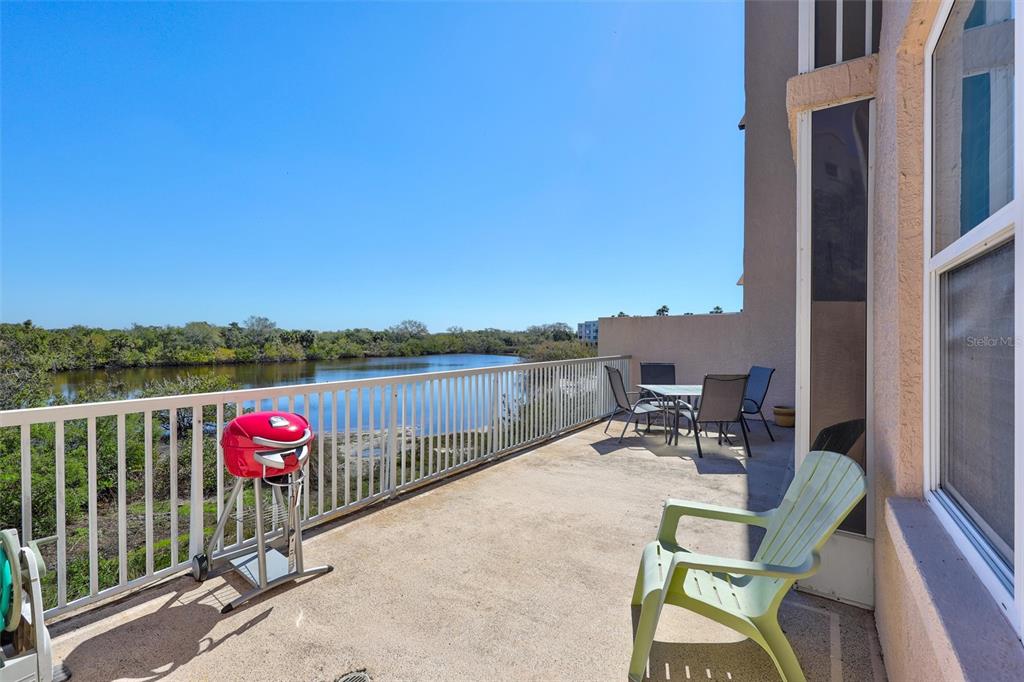 A balcony with a grill, patio furniture, and a view of a lake — 6475 SHORELINE DRIVE UNIT 5102, ST PETERSBURG, FL