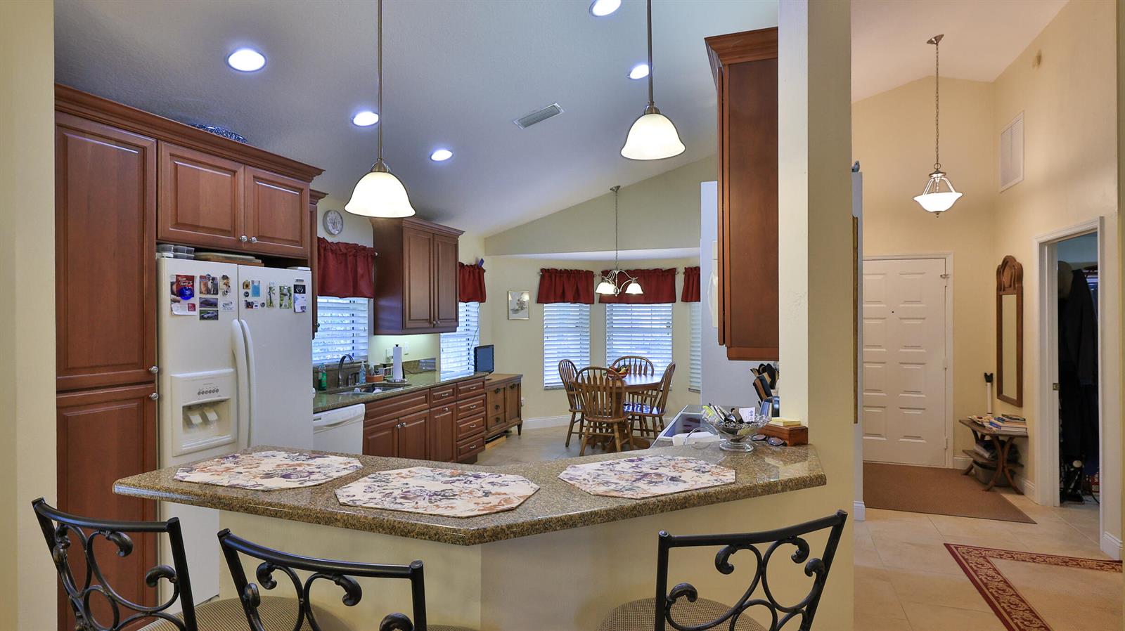 A kitchen with wood cabinets, granite countertops, and a breakfast bar overlooks a dining area — 234 Braeburn Circle, FL 32114, FL