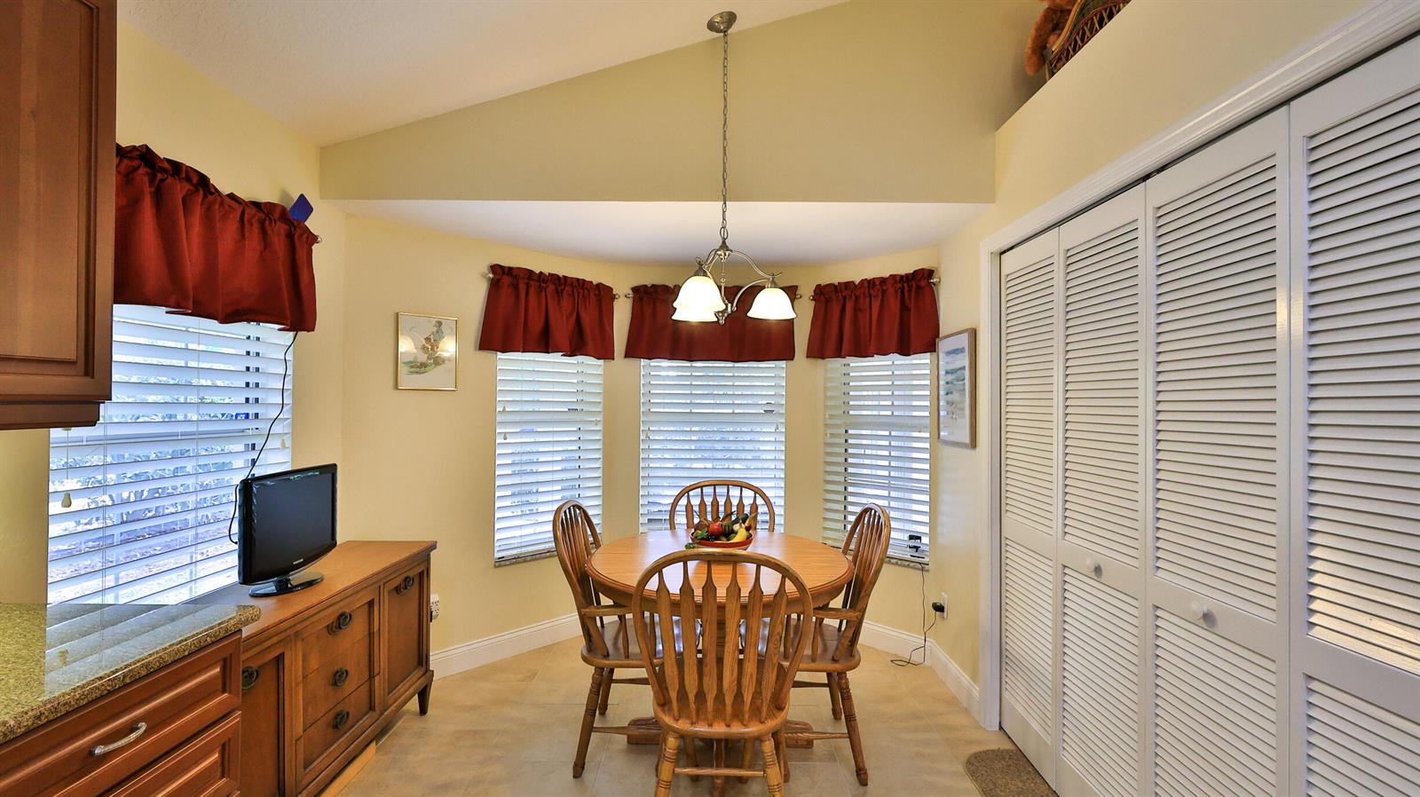 A dining area features a wooden table, chairs, a light fixture, and louvered closet doors — 234 Braeburn Circle, FL 32114, FL