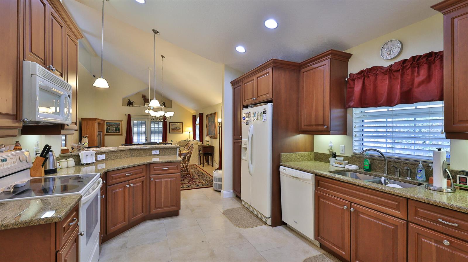 A kitchen with wood cabinets, granite countertops, white appliances, and an open view to the living area — 234 Braeburn Circle, FL 32114, FL