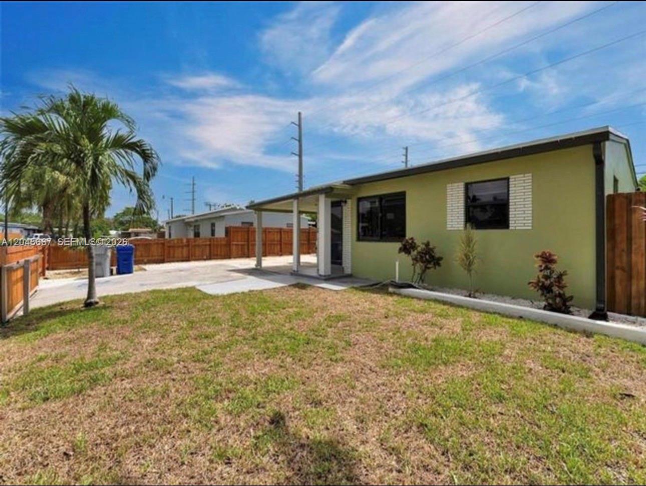 A single-story house with light green siding features a covered porch and a grassy yard — 2730 NE 16th Ave # 0, Pompano Beach FL 33064, POMPANO BEACH, FL
