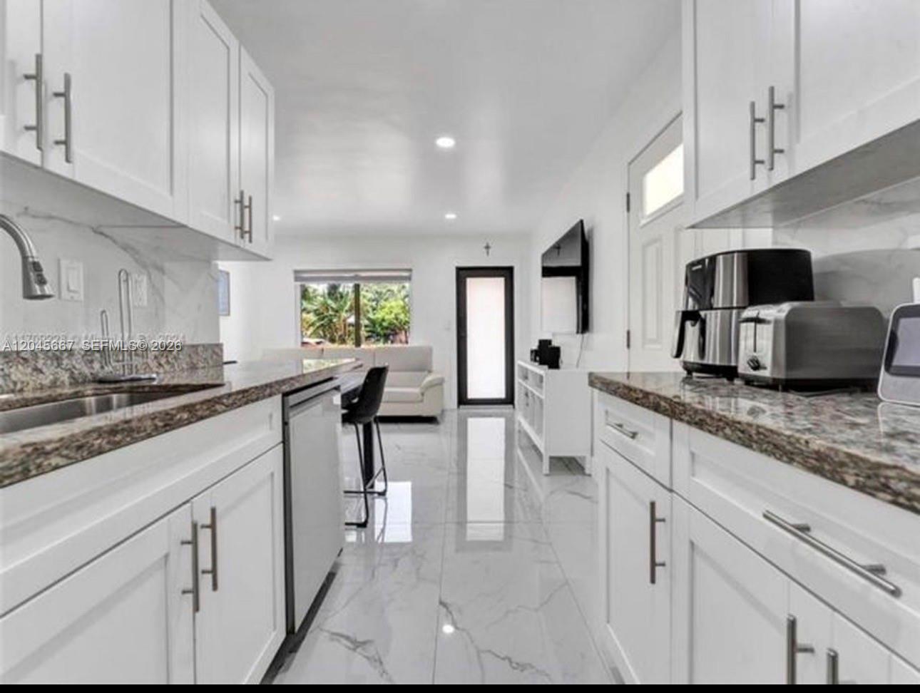 A modern kitchen with white cabinets, granite countertops, and light tile flooring — 2730 NE 16th Ave # 0, Pompano Beach FL 33064, POMPANO BEACH, FL