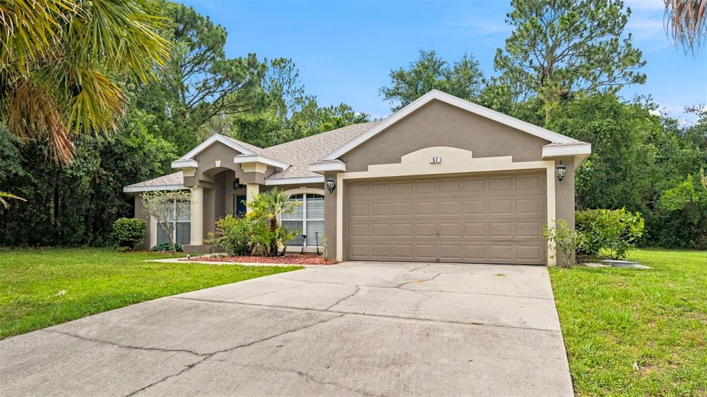 A single-story house with a beige stucco exterior, a two-car garage, and a concrete driveway — 57 PINE DRIVE, HOMOSASSA, FL