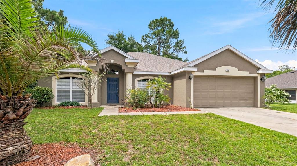 A single-story house with a tan stucco exterior, a blue front door, and a garage — 57 PINE DRIVE, HOMOSASSA, FL