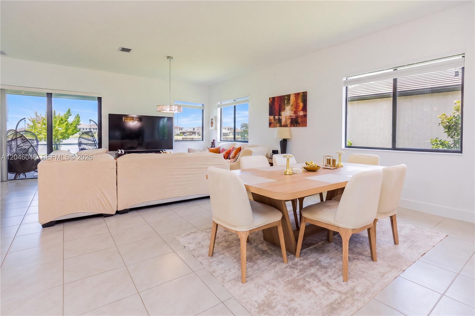 A bright open-concept living and dining area features tile floors, a large sofa, and windows — 5261 LAMONE LN, Ave Maria FL 33142, AVE MARIA, FL
