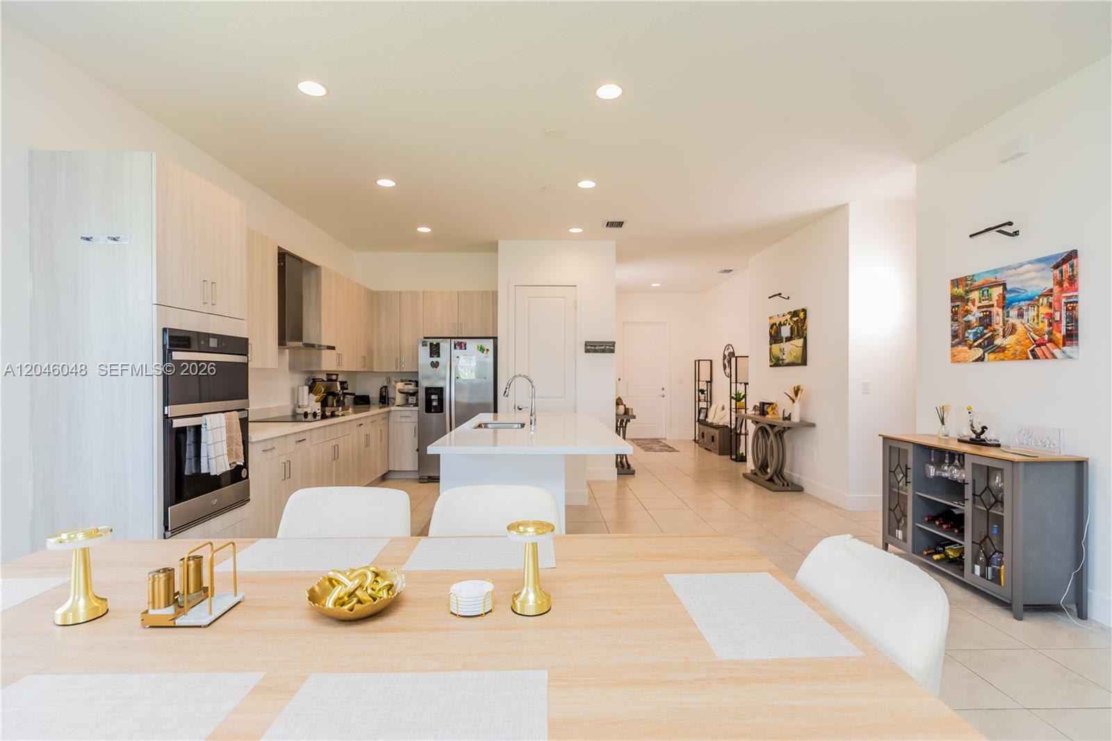 A modern kitchen with light wood cabinets and a central island overlooks a dining area — 5261 LAMONE LN, Ave Maria FL 33142, AVE MARIA, FL