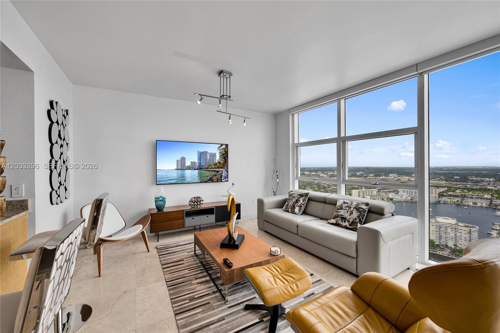 A modern living room features a gray sofa, wood coffee table, and floor-to-ceiling windows — 1830 S Ocean Dr # 4807, Hallandale Beach FL 33009, HALLANDALE BEACH, FL