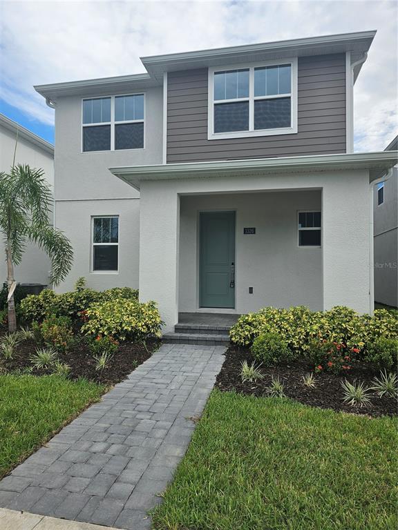 A two-story house features a light-colored stucco exterior, a gray front door, and a paver walkway — 1526 RIDGEBACK LANE, APOPKA, FL