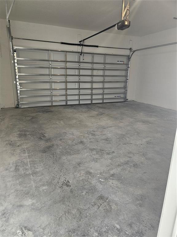 An empty garage features a concrete floor, white walls, and a metal sectional door — 1526 RIDGEBACK LANE, APOPKA, FL