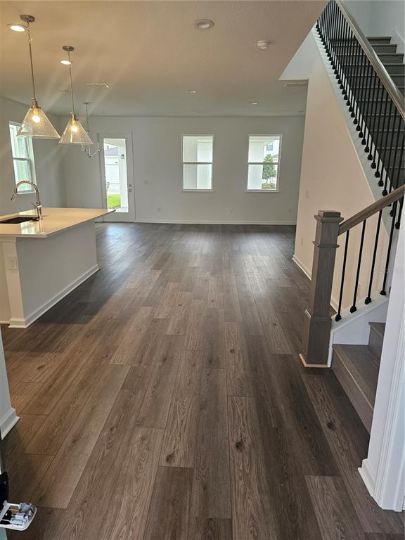 An open-concept kitchen and living area features wood-look flooring, a central island, and a staircase — 1526 RIDGEBACK LANE, APOPKA, FL