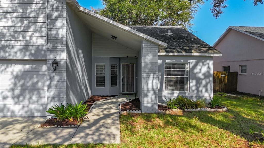 A gray house with a brick facade, a covered entryway, and a concrete walkway — 13436 SILVERCREEK DRIVE, RIVERVIEW, FL