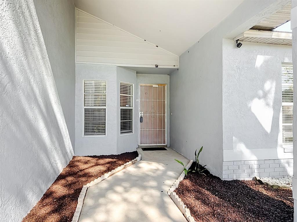 A concrete walkway leads to the front entrance of a house with a security door — 13436 SILVERCREEK DRIVE, RIVERVIEW, FL