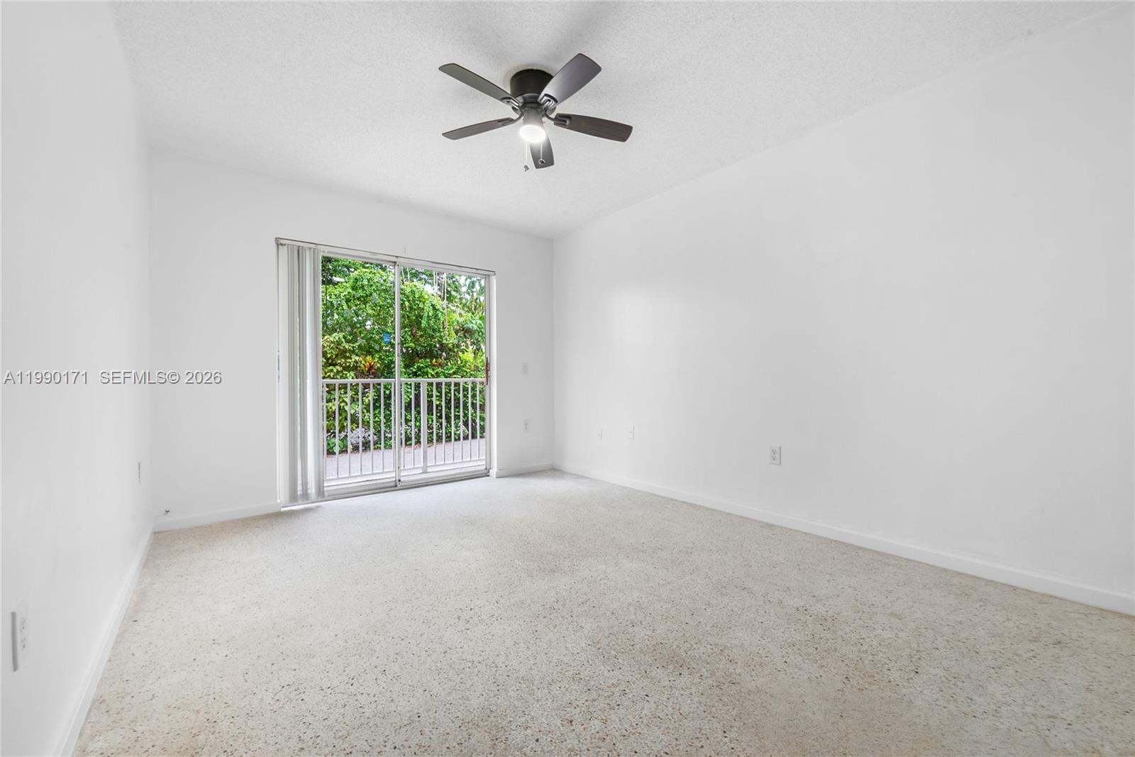 An empty room features white walls, beige carpet, a ceiling fan, and a sliding glass door — 2661 SW 11th St # 8, Miami FL 33135, MIAMI, FL