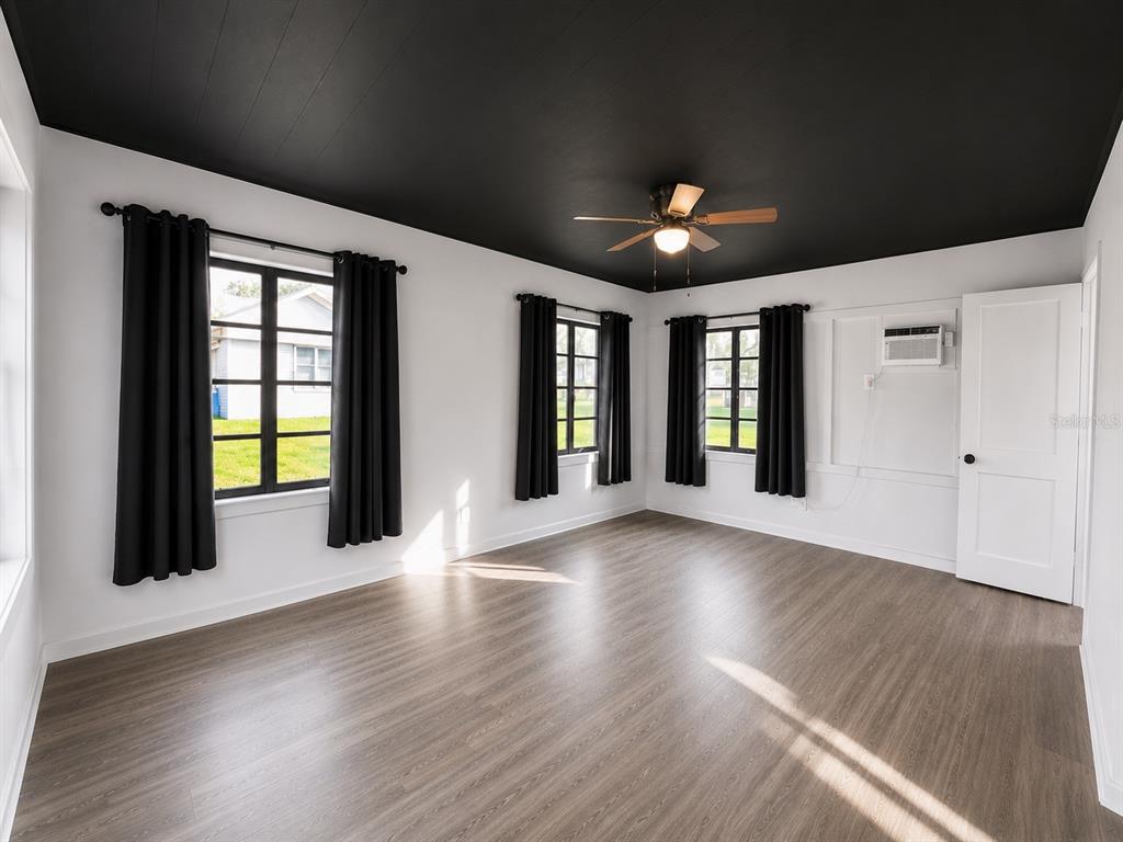 A room with white walls, a black ceiling, wood-look flooring, and black window curtains — 8010 SE US HIGHWAY 301 UNIT 4A, HAWTHORNE, FL