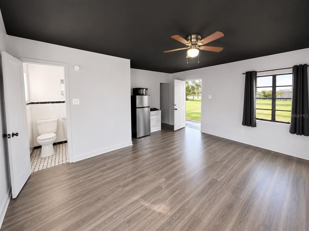 A room with light wood-look flooring, a black ceiling, a ceiling fan, and an attached bathroom — 8010 SE US HIGHWAY 301 UNIT 4A, HAWTHORNE, FL