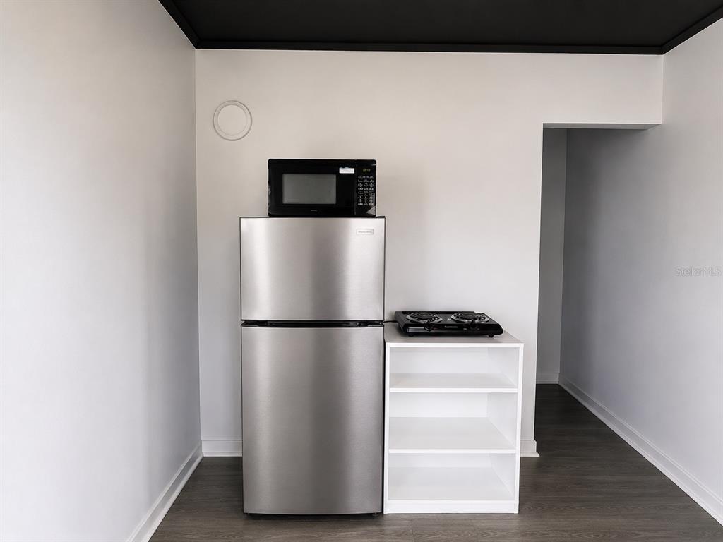 A small kitchen area features a stainless steel refrigerator, a microwave, and a portable stovetop — 8010 SE US HIGHWAY 301 UNIT 4A, HAWTHORNE, FL