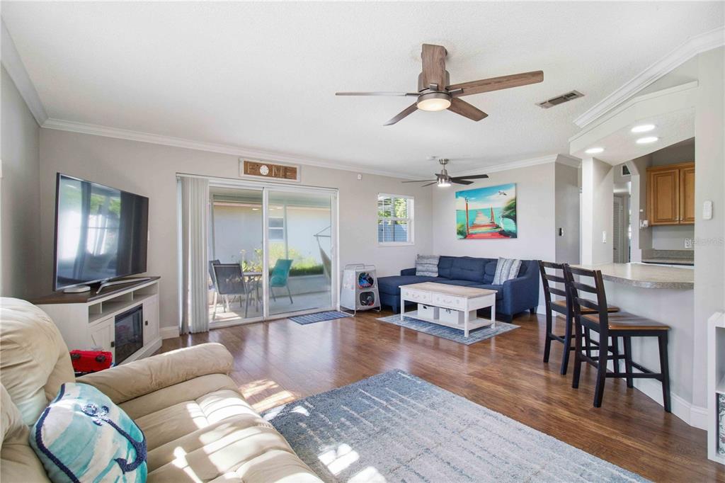 A living room with wood floors, a blue sofa, a TV console, and a breakfast bar — 6116 DARTMOUTH DRIVE, BRADENTON, FL