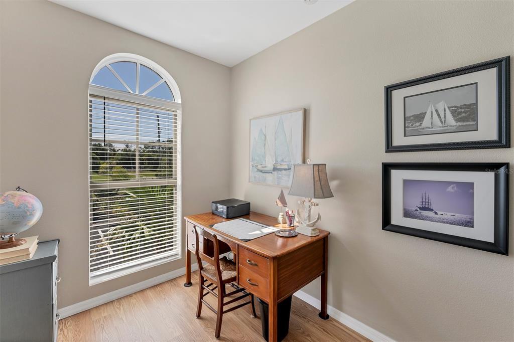A home office features a wooden desk, a chair, a window, and nautical-themed wall art — 3927 CAPE HAZE DRIVE UNIT 204, ROTONDA WEST, FL