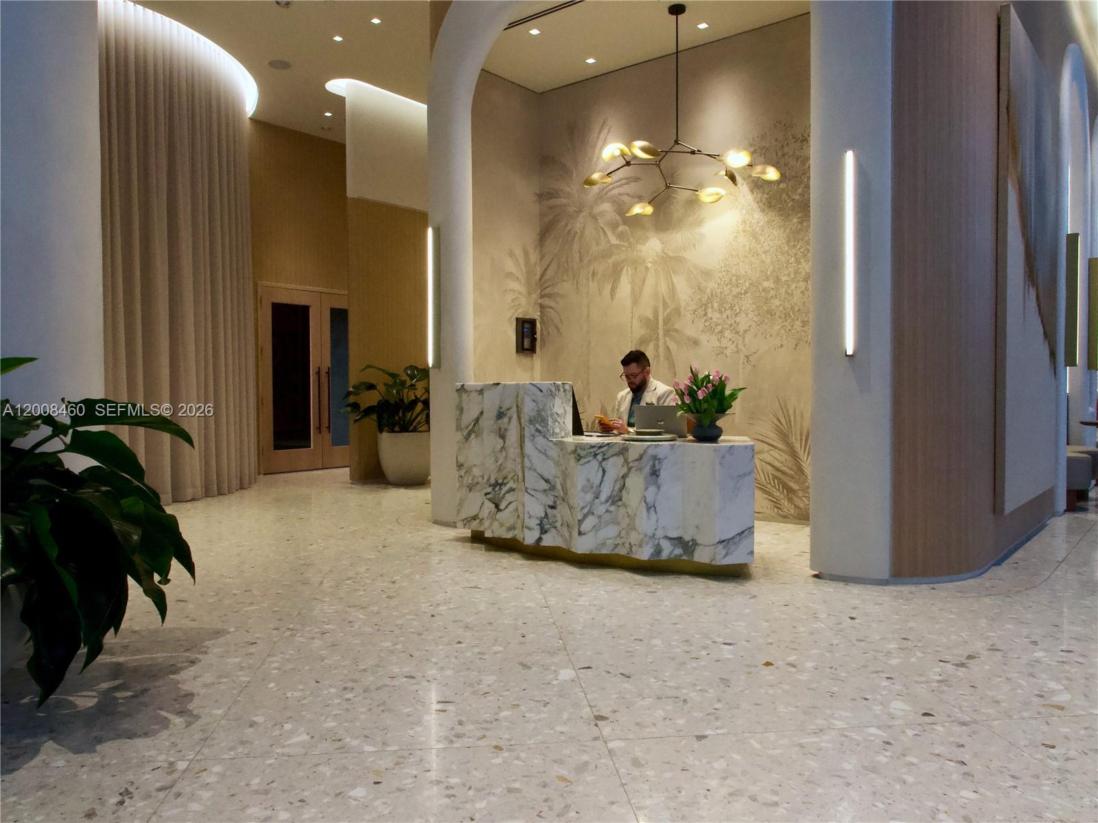 A reception desk with a marble finish sits in a modern lobby with terrazzo flooring — 77 SE 5th Street # 4014, Miami FL 33131, MIAMI, FL