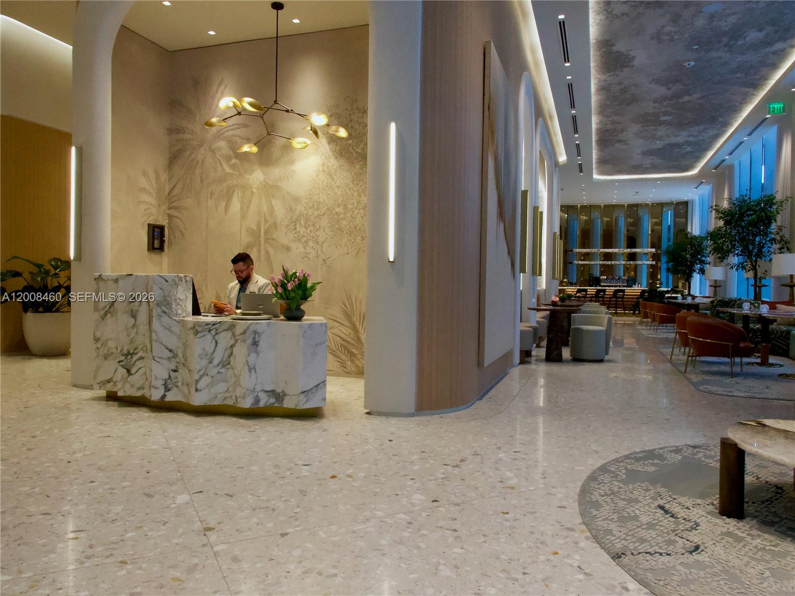 A modern hotel lobby features a marble reception desk, a mural, and lounge seating areas — 77 SE 5th Street # 4014, Miami FL 33131, MIAMI, FL