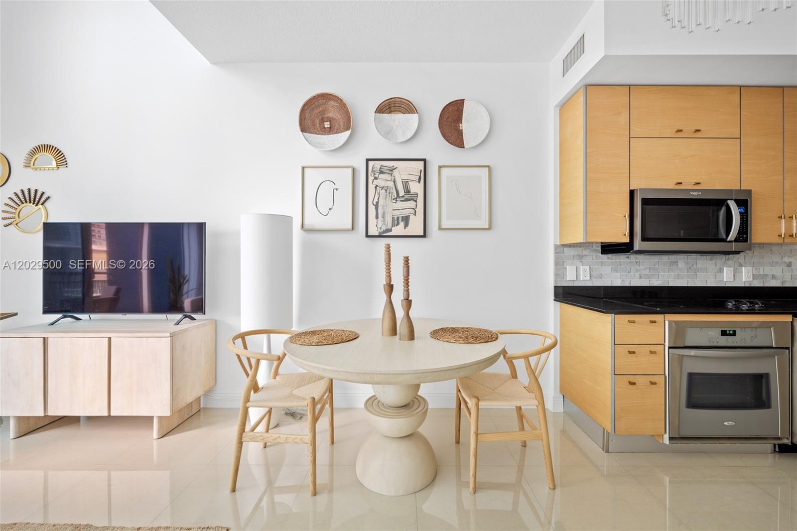A dining area features a round table, two wooden chairs, and wall-mounted decorative art — 60 SW 13th St # 3414, Miami FL 33130, MIAMI, FL