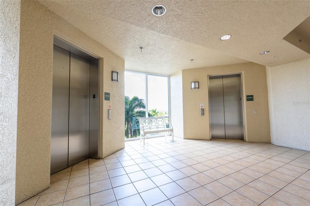 An elevator lobby with tile flooring, two stainless steel elevators, and a white bench — 3414 HANCOCK BRIDGE PARKWAY UNIT 505, NORTH FORT MYERS, FL