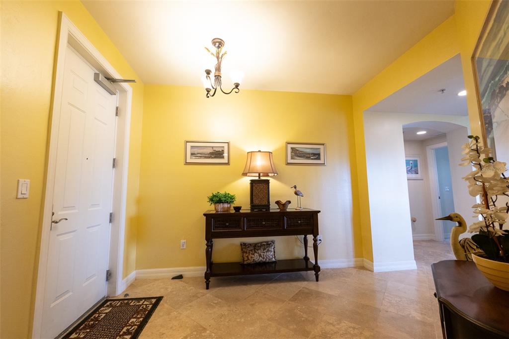 A foyer with yellow walls, tile flooring, a console table, and a chandelier — 3414 HANCOCK BRIDGE PARKWAY UNIT 505, NORTH FORT MYERS, FL