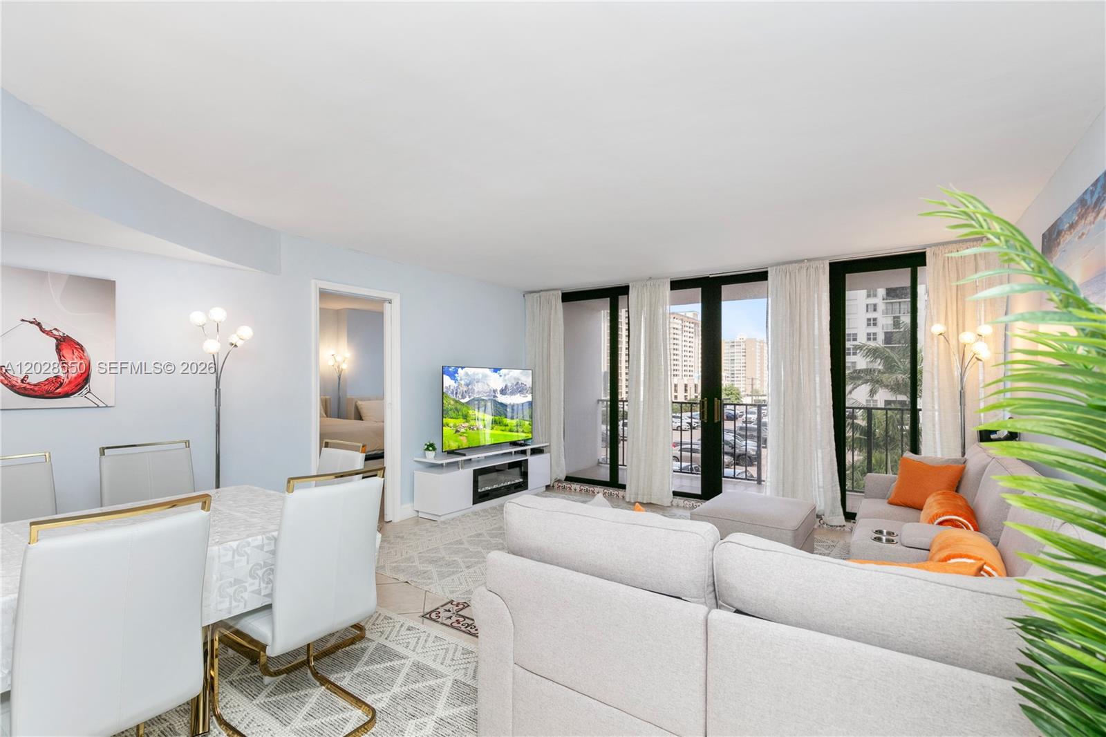 A living and dining area features light gray furniture, a television, and a balcony view — 2401 S Ocean Dr # 404, Hollywood FL 33019, HOLLYWOOD, FL