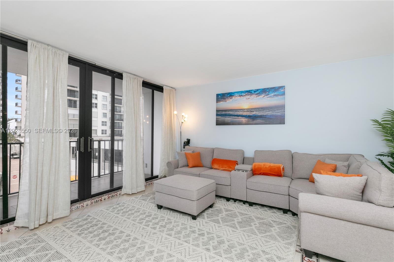 A living room features a gray sectional sofa, an ottoman, and sliding glass balcony doors — 2401 S Ocean Dr # 404, Hollywood FL 33019, HOLLYWOOD, FL