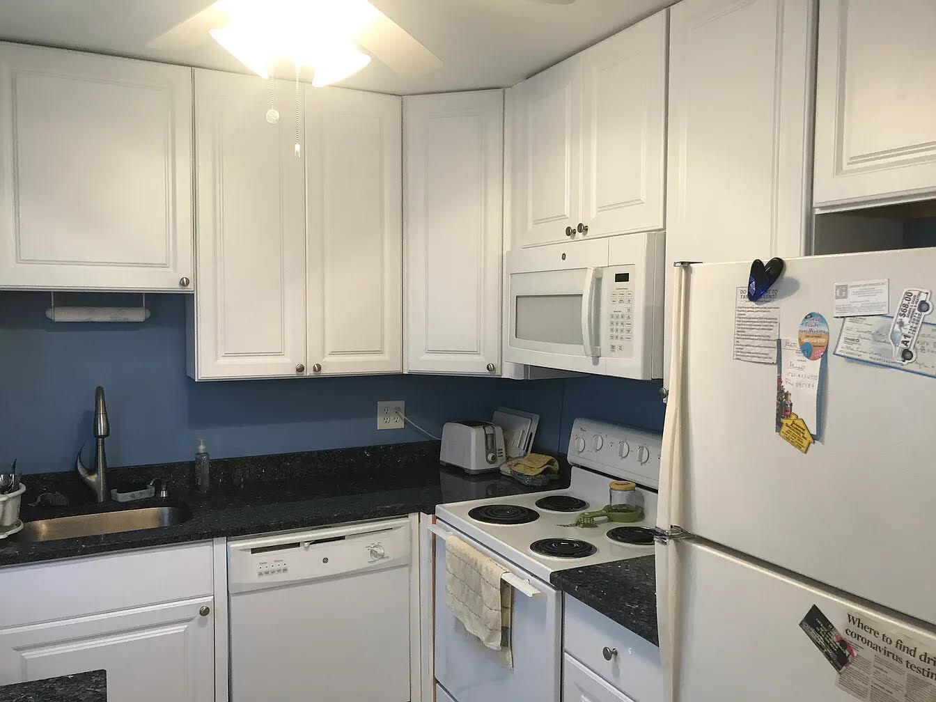 A kitchen with white cabinets, dark countertops, a white stove, and a white dishwasher — 596 Saxony M, Delray Beach FL 33446, DELRAY BEACH, FL