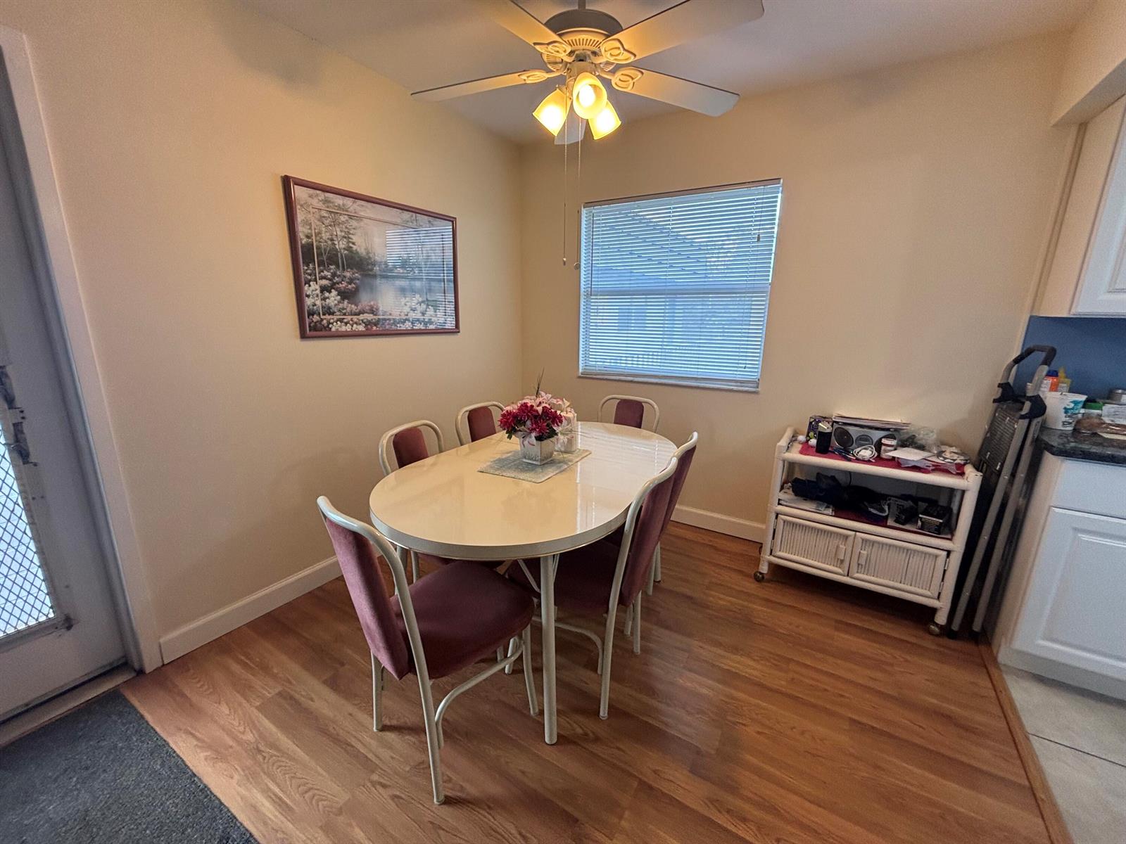 A dining room features a light-colored oval table, six chairs, wood flooring, and a ceiling fan — 596 Saxony M, Delray Beach FL 33446, DELRAY BEACH, FL