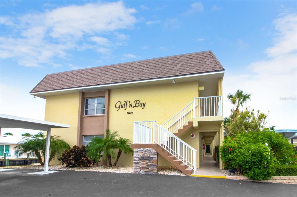 A two-story yellow apartment building with an exterior staircase and a covered parking area — 1400 TARPON CENTER DRIVE UNIT 206, VENICE, FL