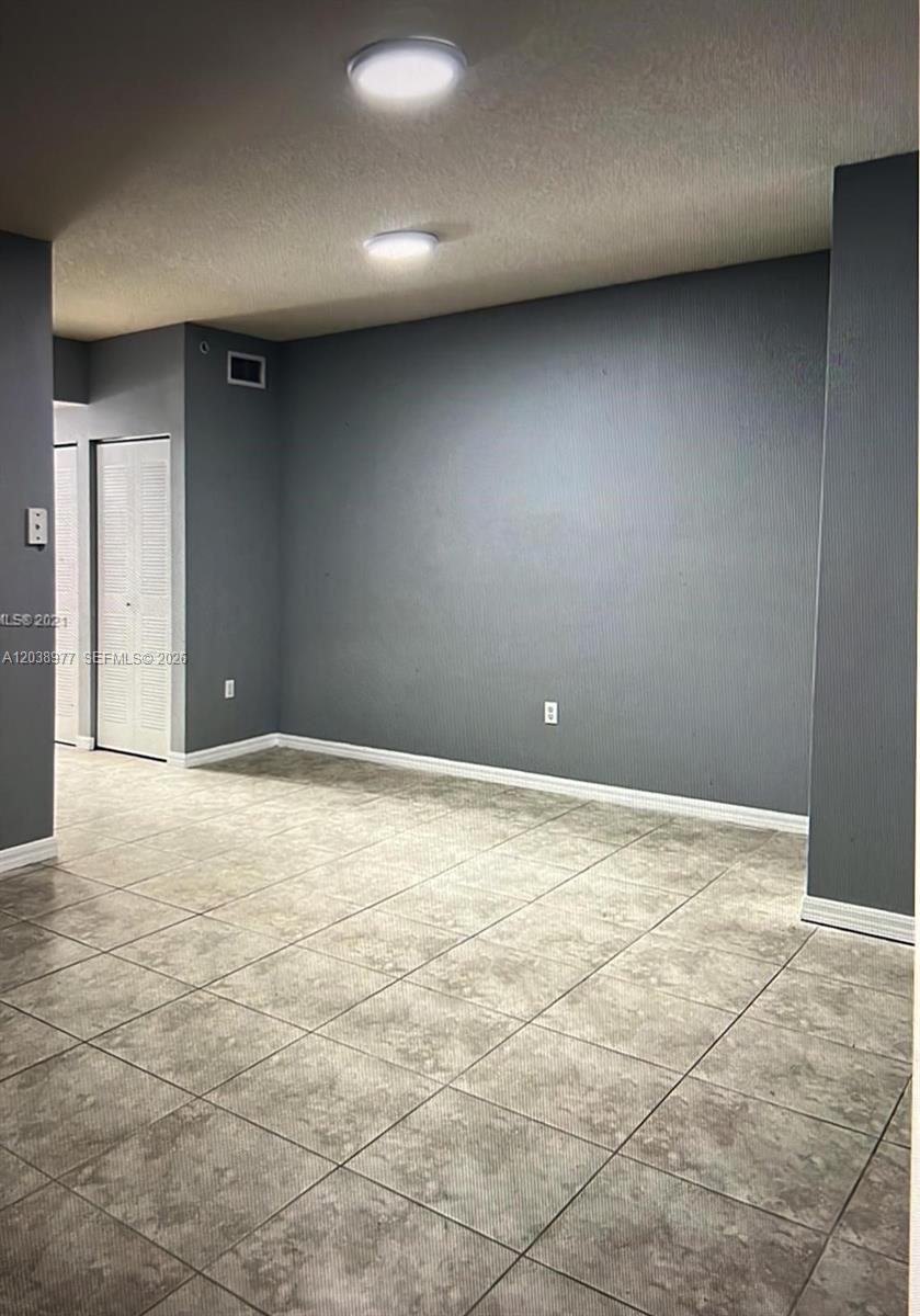An empty room features gray walls, tiled flooring, and two flush-mount ceiling lights — 115 SW 42nd Ave # 206, Miami FL 33134, MIAMI, FL