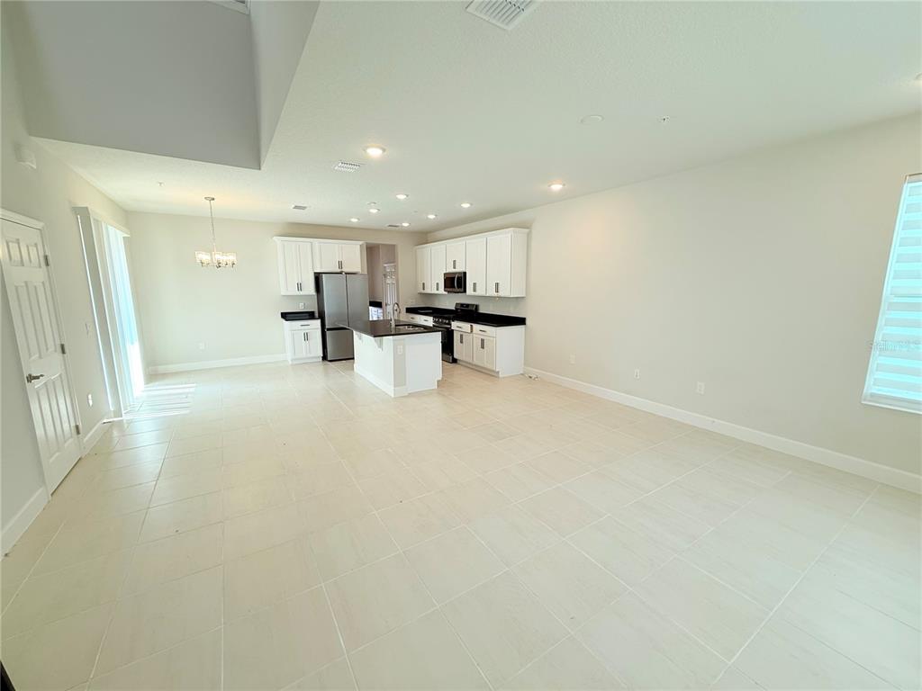 An open-concept kitchen with white cabinets, dark countertops, and tile flooring — 237 STATION LANE, DEBARY, FL