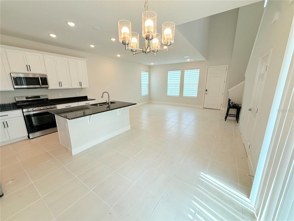 A kitchen with white cabinets, black countertops, and a chandelier over a central island — 237 STATION LANE, DEBARY, FL