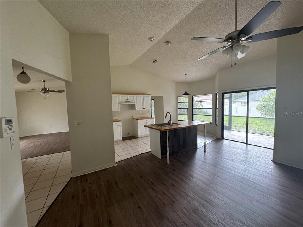 A kitchen with a wooden island and white cabinets opens to a living area — 2378 COMERWOOD DRIVE, SPRING HILL, FL