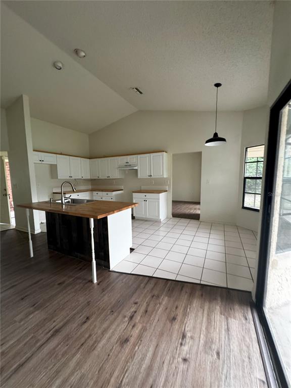 A kitchen features white cabinets, butcher block countertops, a center island, and tile flooring — 2378 COMERWOOD DRIVE, SPRING HILL, FL