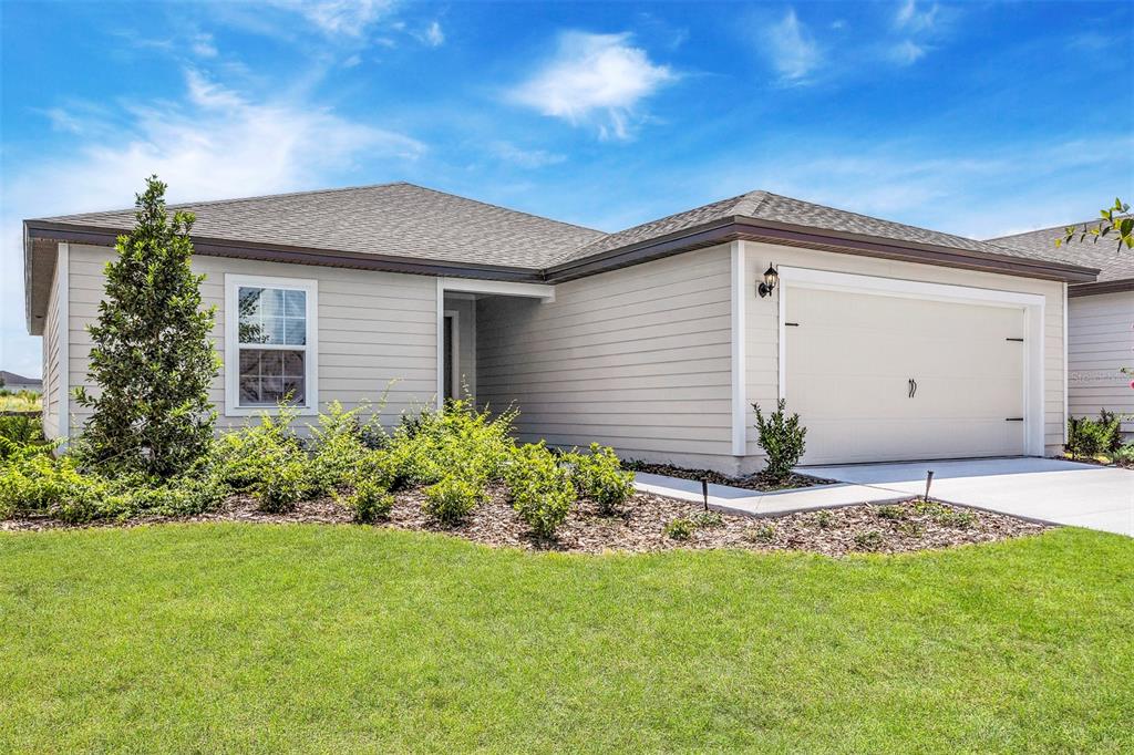 A single-story house with light-colored siding, a two-car garage, and a landscaped front yard — 2674 SW 165TH STREET ROAD, OCALA, FL
