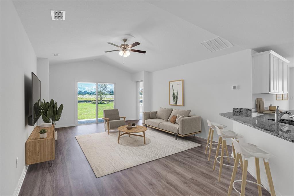 A living room with a vaulted ceiling, sliding glass doors, and an adjacent kitchen island — 2674 SW 165TH STREET ROAD, OCALA, FL